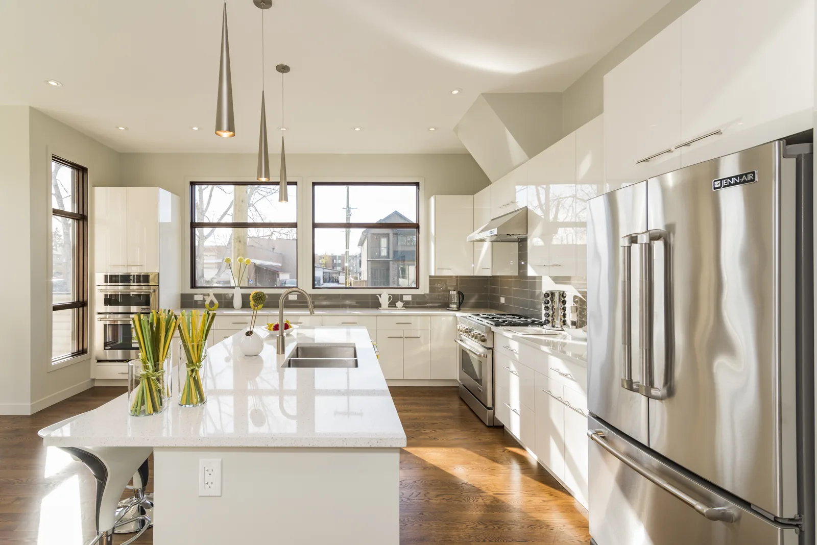 A bright, empty kitchen with warm wooden floors and a generous island